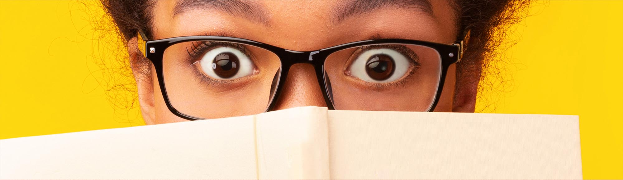 a person reading a book with an excited, wide-eyed look