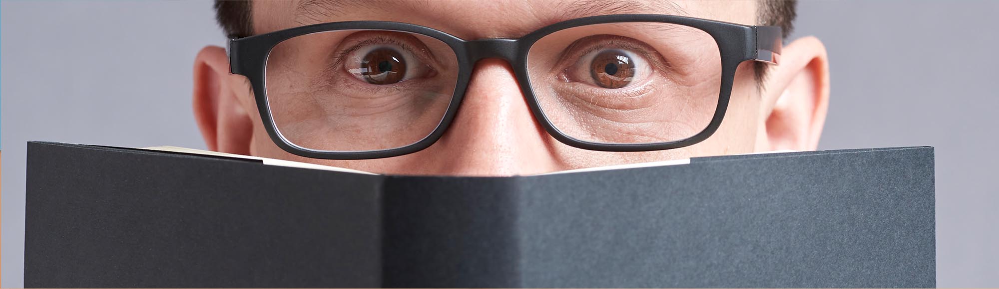 a person reading a book with an excited, wide-eyed look