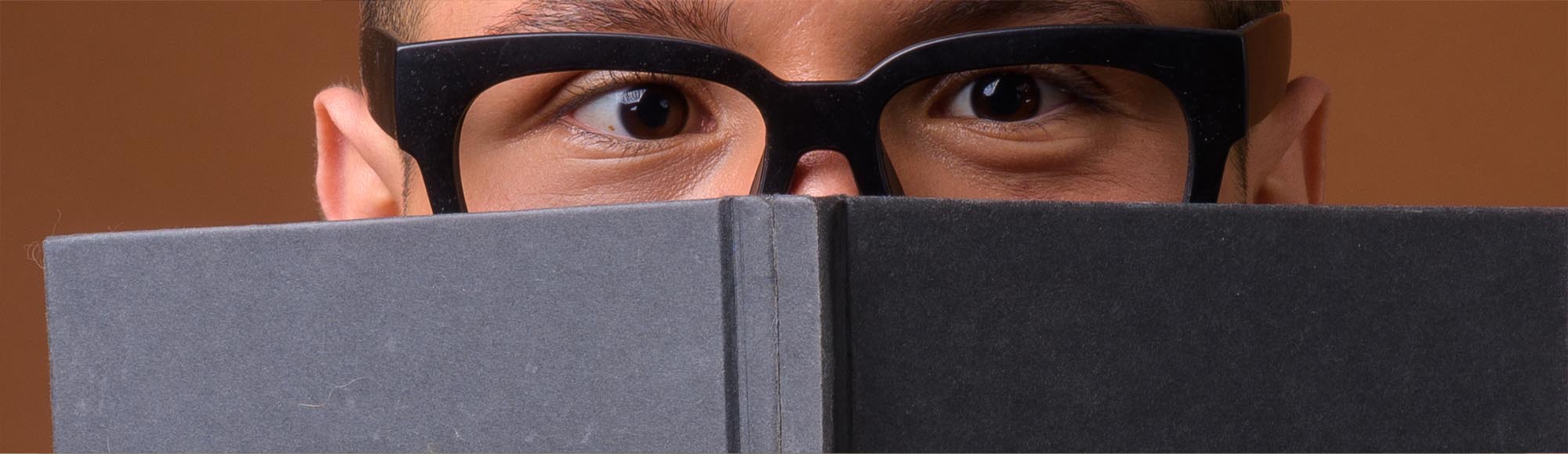 a person reading a book with an excited, wide-eyed look