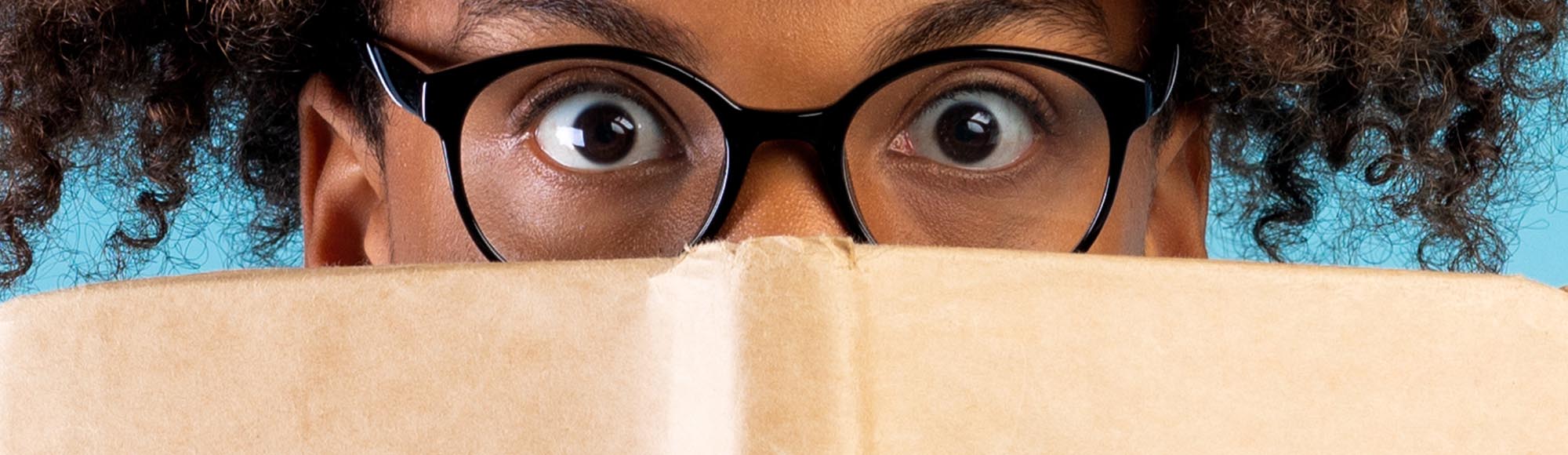 a person reading a book with an excited, wide-eyed look