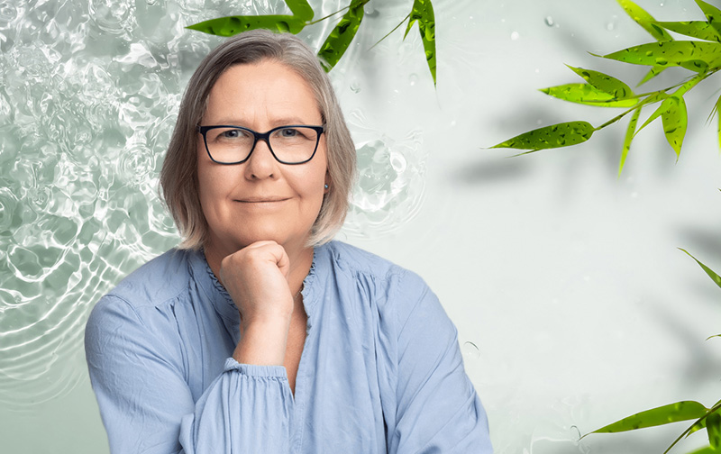 Dr. Emma Kell in front of an image of a pond with ripples, representing the concept of wellbeing in the face of crisis